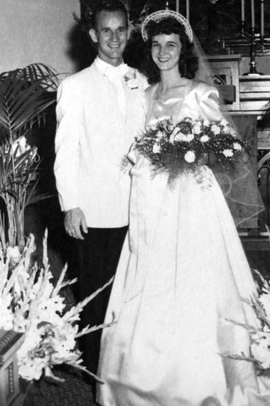 Irene holding a bouquet and standing beside her husband, both in wedding attire.